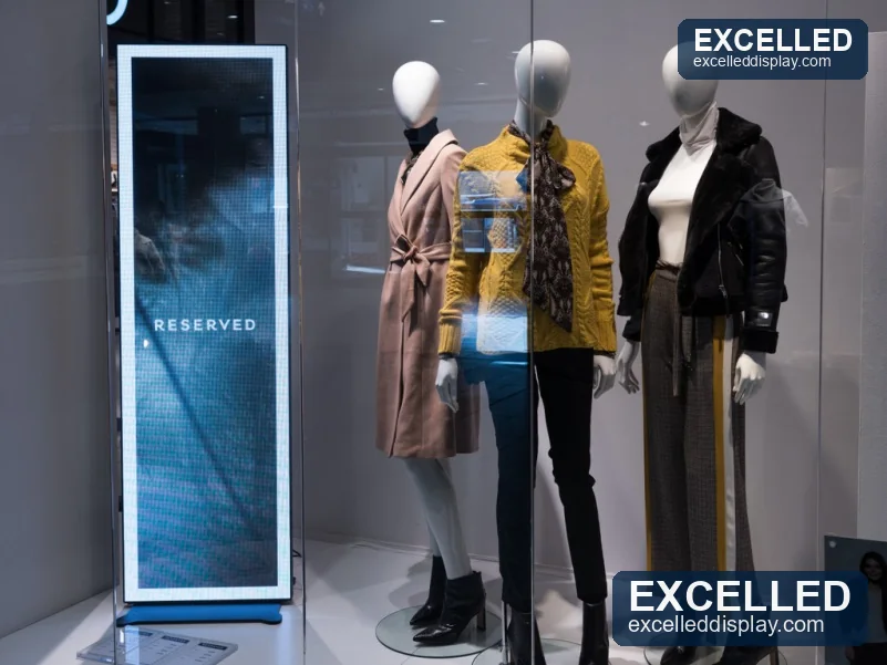 A 1890x560mm LED poster display installed inside a glass retail display case beside mannequins