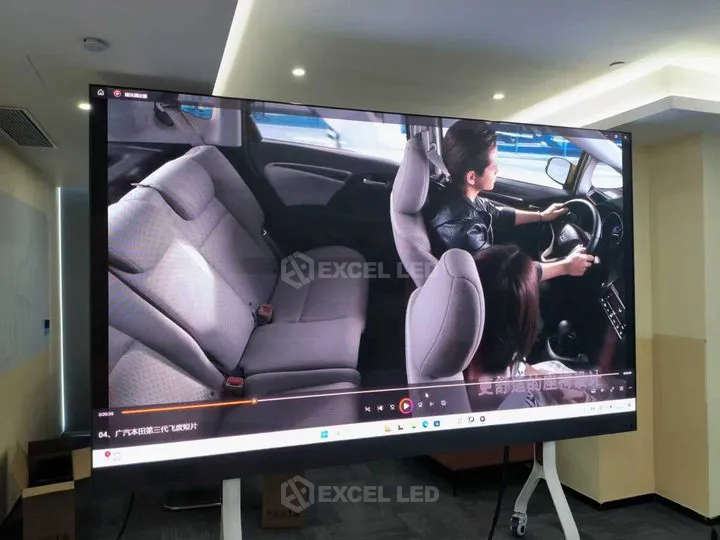 All-in-one LED display with flip-chip COB panel running a video in a corporate meeting room on a mobile stand